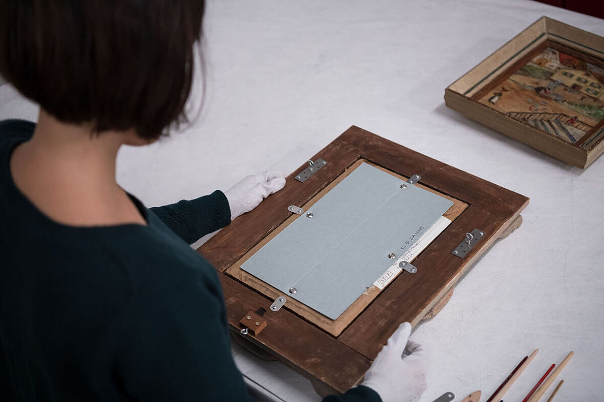 Registrarin untersucht die Rückseite eines Bildes