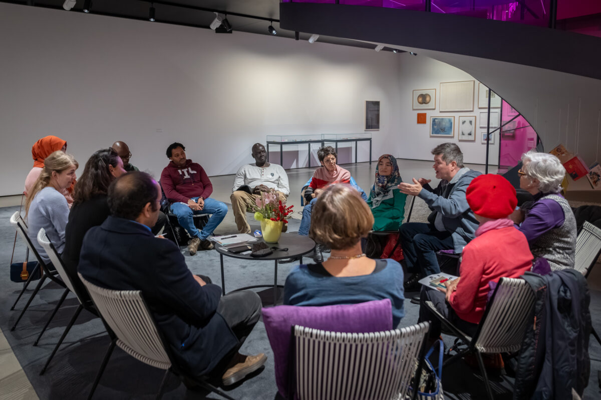 Personen sitzen im Kreis im Freiraum des Aargauer Kunsthauses und diskutieren