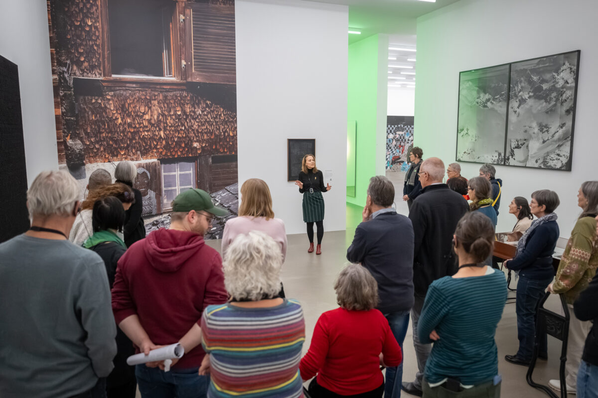 Eine Menge an Personen hört einer Vermittlerin zu in einem Ausstellungsraum im Aargauer Kunsthaus