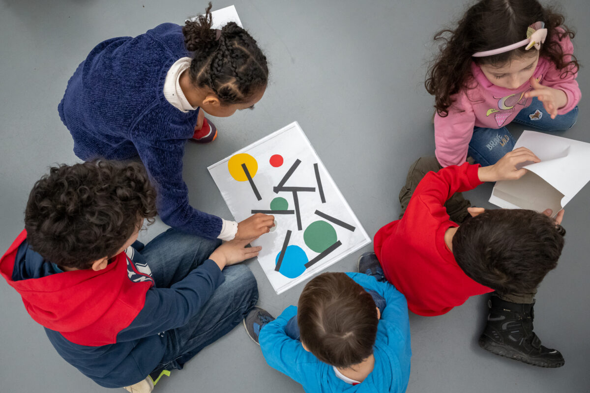 Eine Gruppe von Kindern, die ein abstraktes Bild am Boden zusammensetzen