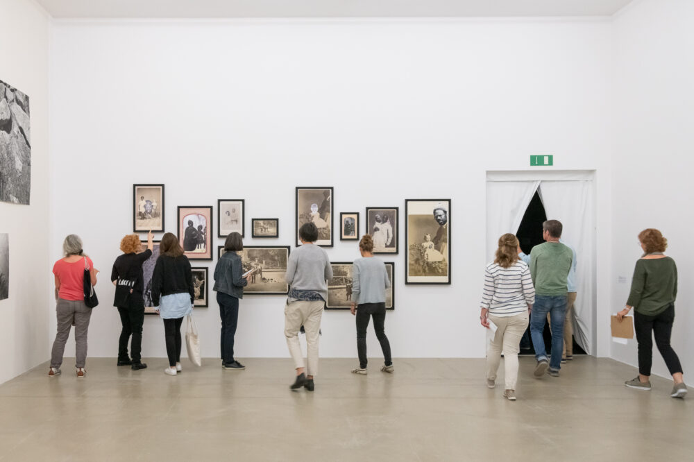 Lehrpersonen sehen sich Bilder in ein Ausstellung an.