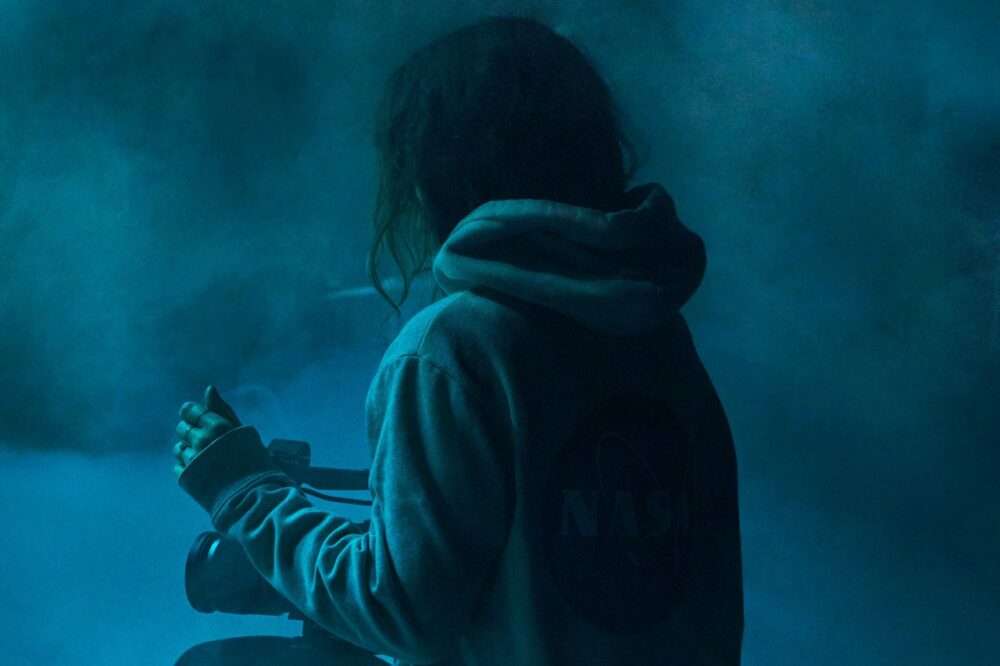 Ein Foto einer Frau, die von hinten her fotografiert wird, sie sitzt im Nebel