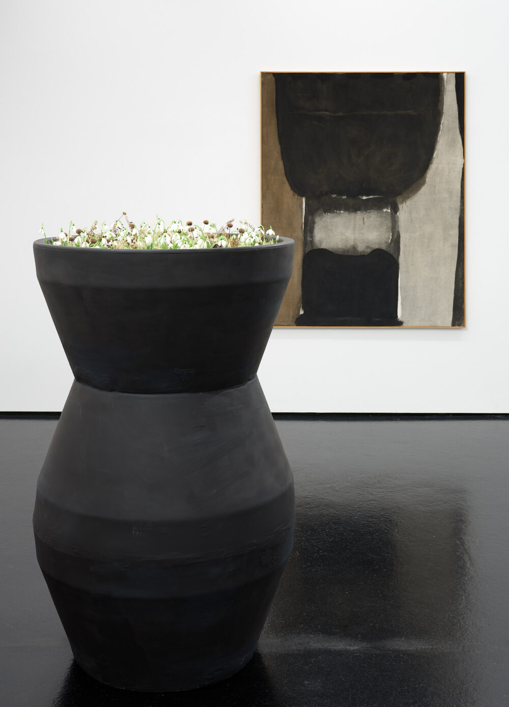 Grosse dunkle Vase vor Bild von einem Krug/Behälter