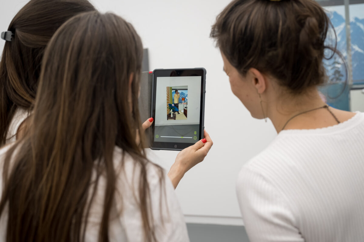 Drei Personen schauen sich animierte Kunst auf einem Tablet an.