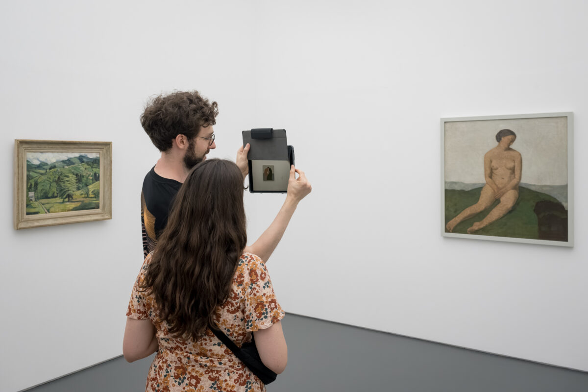 Zwei Personen schauen sich im Aargauer Kunsthaus auf einem Tablet animierte Kunst an.