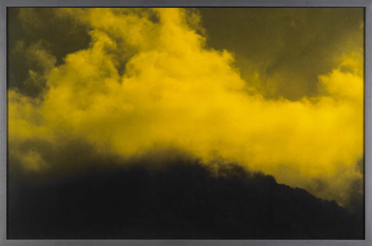 Gelb eingefärbtes Foto einer Wolke, die über einen Berg zieht