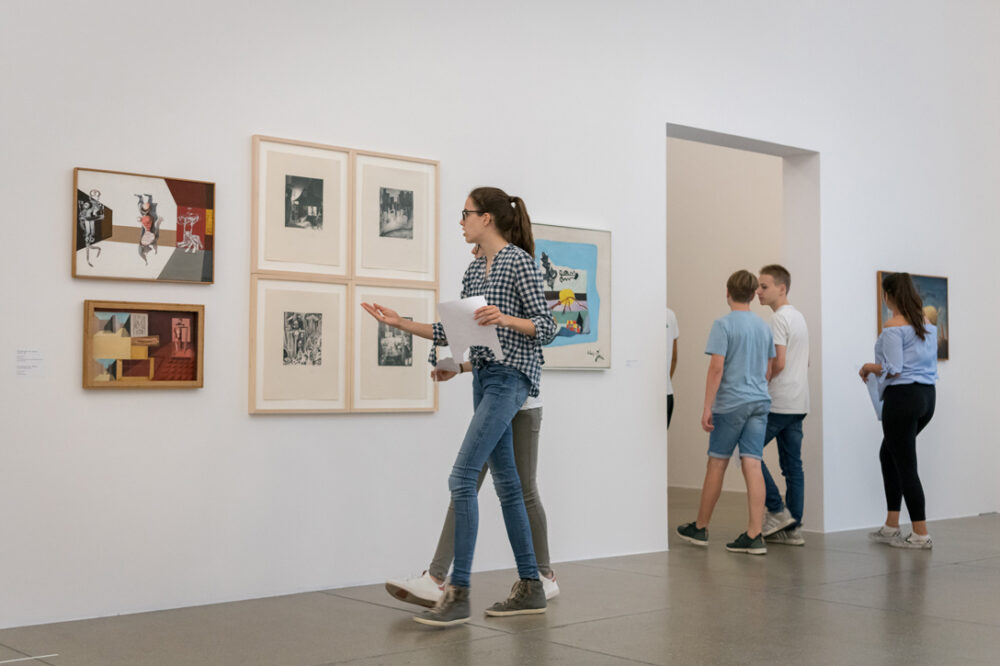 Schülerinnen und Schüler gehen durch die Ausstellung und entdecken einzelne Kunstwerke