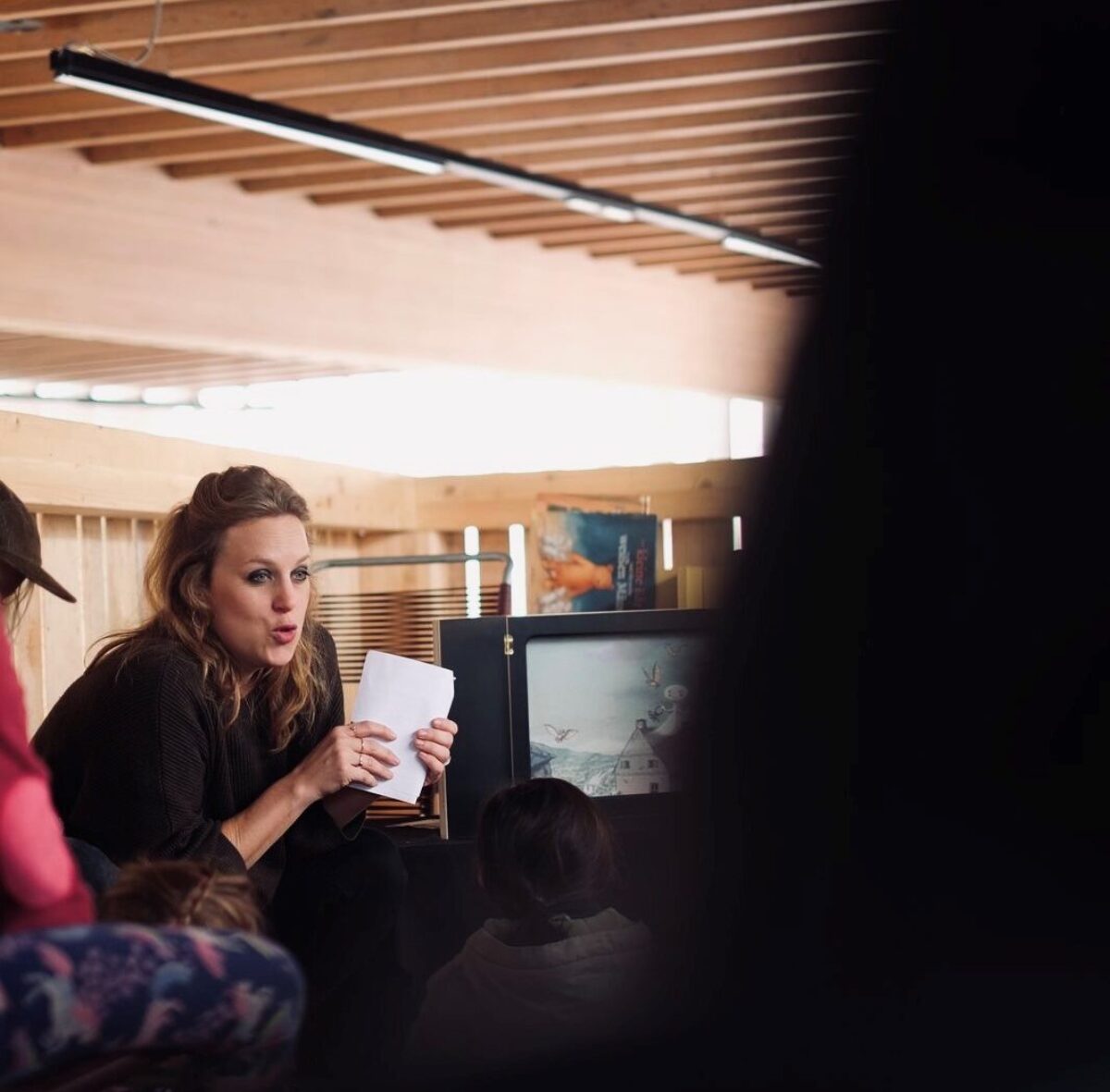 Eine Frau liest aus einem Buch und zeigt dem Publikum eine Seite