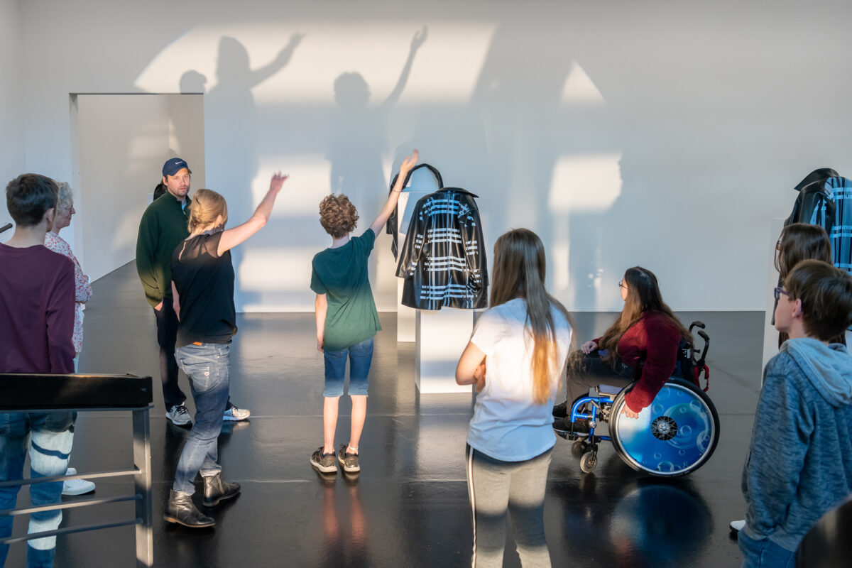 Ein kunstschaffender erklärt während des inklusiven Ferienworkshops einer Gruppe von Jugendlichen sein Schaffen anhand eines Schattenspiels
