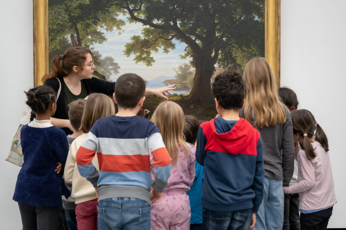 Eine Vermittlerin erklärt einer Klasse ein Werk aus der Sammlung