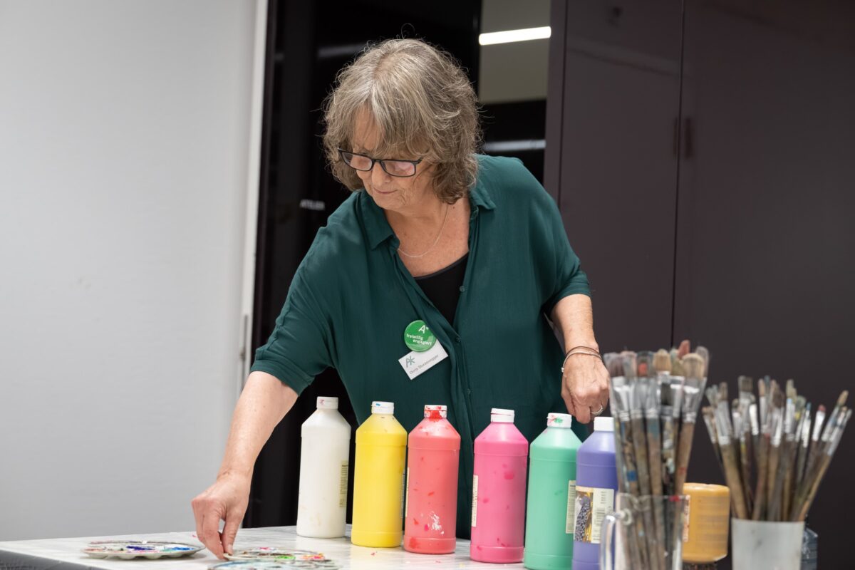 Eine Freiwillige hilft im Offenen Atelier bei der Bereitstellung des Malmaterials