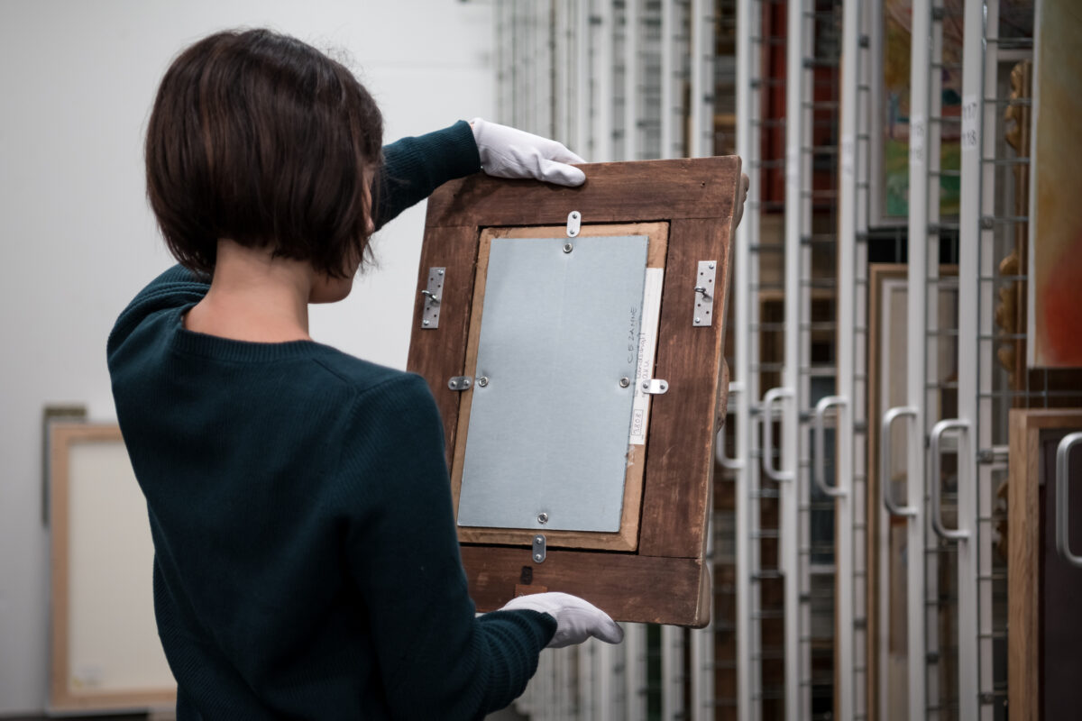 Registrarin nimmt ein BIld aus dem Sammlungsdepot