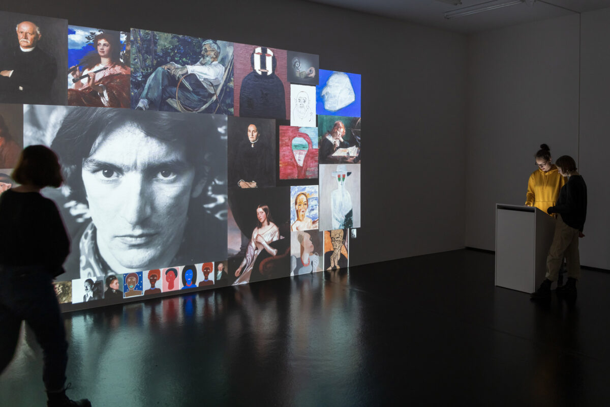 Personen kuratieren eine virtuelle Ausstellung, die an eine Wand gebeamt wird.