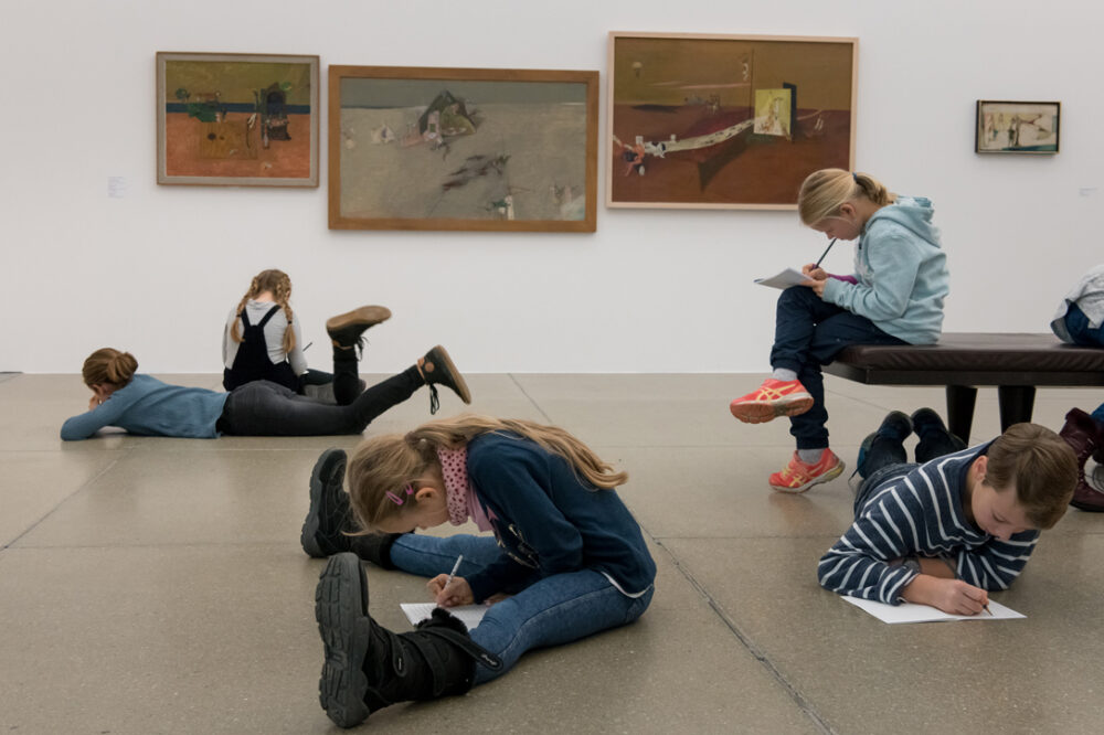 Kinder machen Notizen und zeichnen in einem Ausstellungsraum