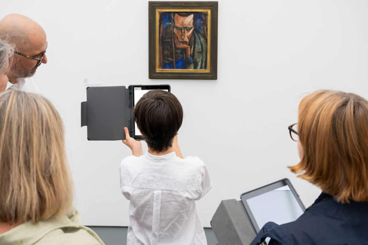Kinder schauen mit einem Tablet in der Hand auf ein Sammlungswerk und erleben dank Augmented Reality eine animierte Version des Kunstwerkes
