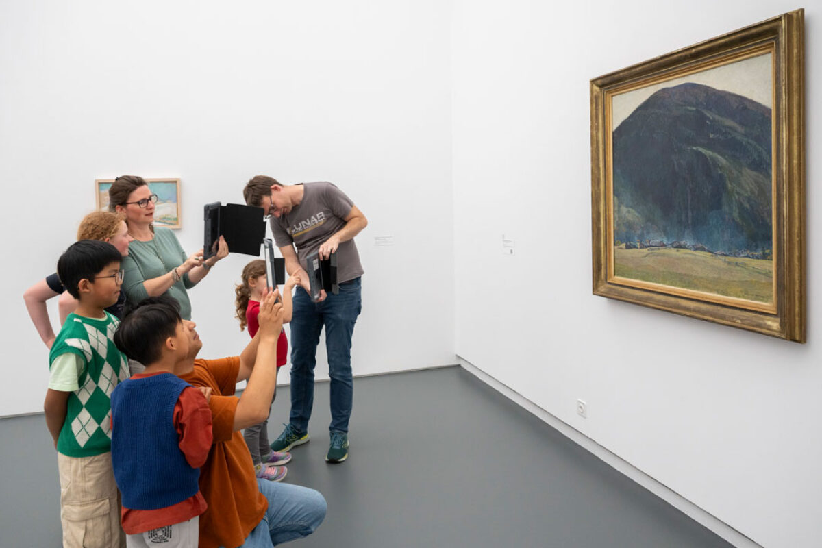 Kinder schauen mit einem Tablet in der Hand auf ein Sammlungswerk und erleben dank Augmented Reality eine animierte Version des Kunstwerkes
