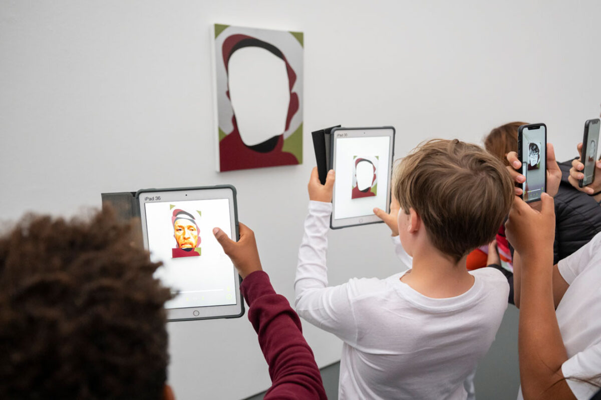 Kinder schauen mit einem Tablet in der Hand auf ein Sammlungswerk und erleben dank Augmented Reality eine animierte Version des Kunstwerkes