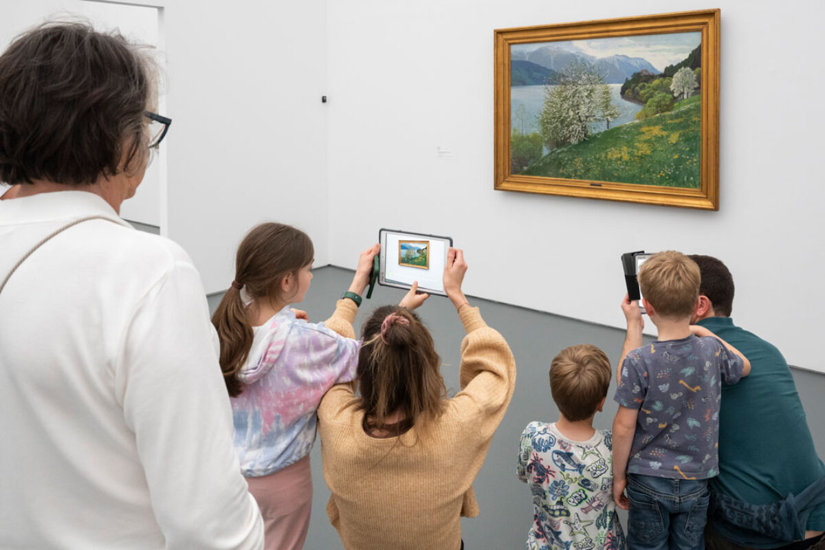 Kinder schauen mit einem Tablet in der Hand auf ein Sammlungswerk und erleben dank Augmented Reality eine animierte Version des Kunstwerkes