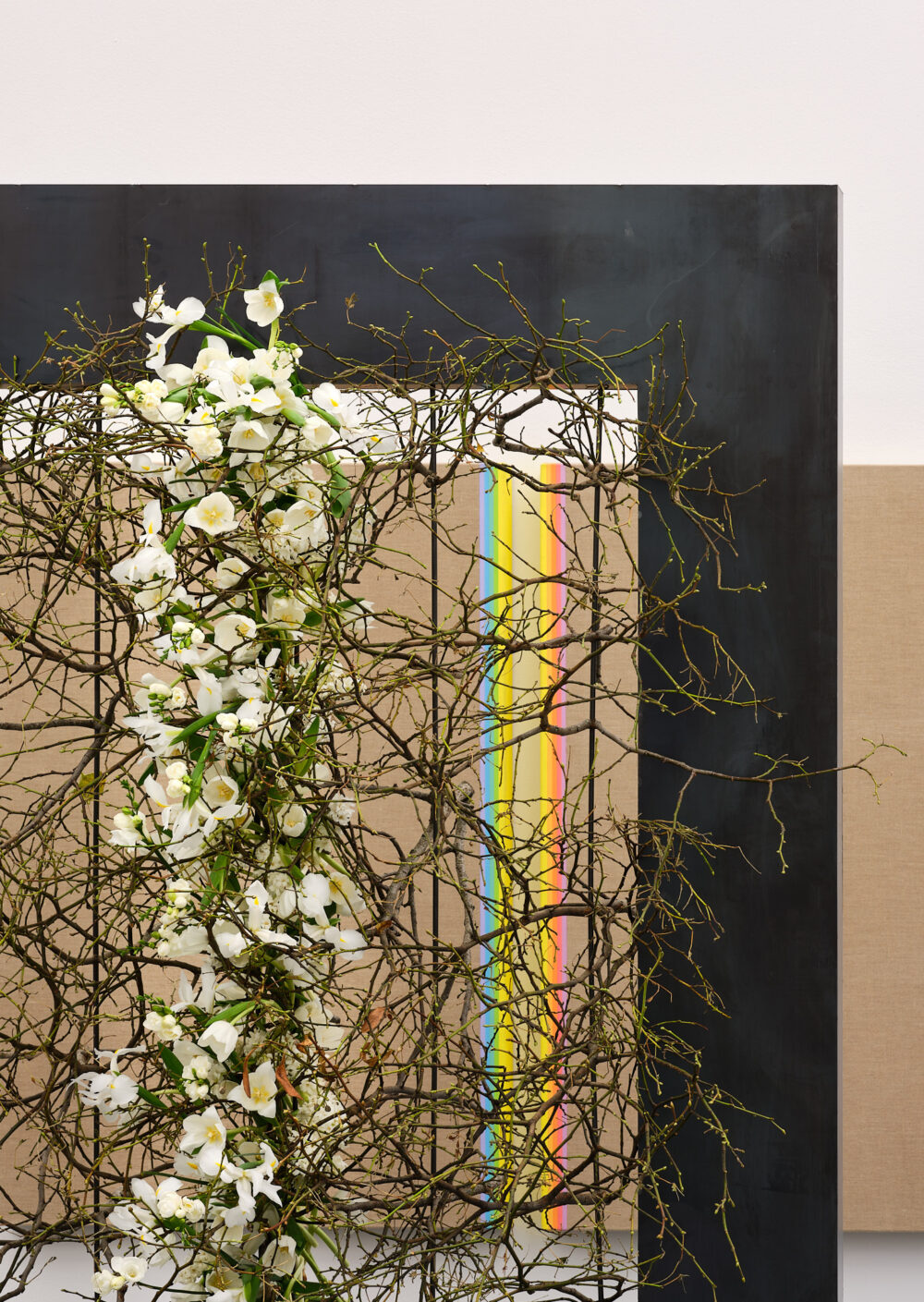 Foto einer Blumeninstallation in Front eines abstrakten Kunstwerkes mit einem Farbverlauf