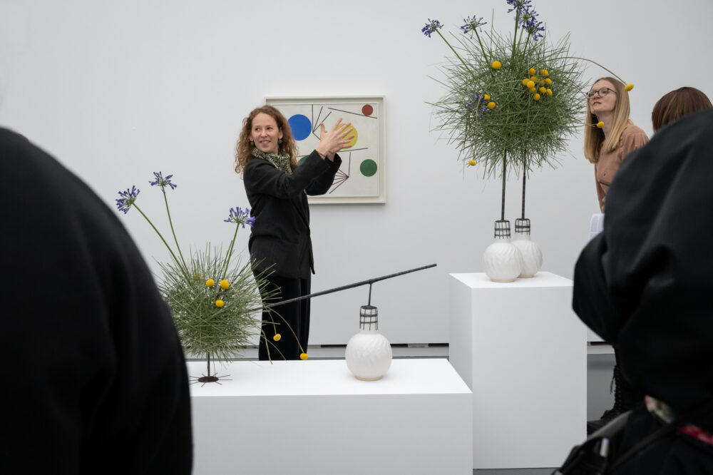Eine Gebärdendolmetscherin stellt ein Kunstwerk mit Blumen vor
