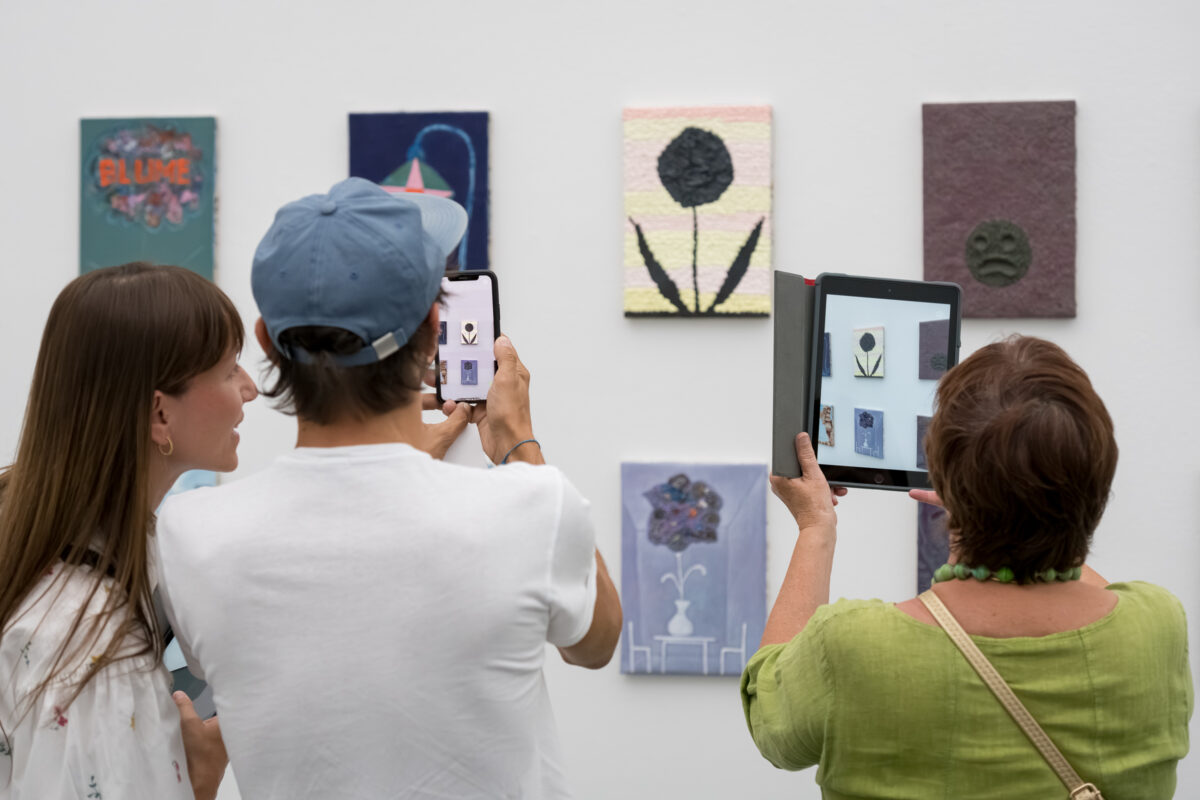 Personen schauen sich mit Tablets animierte Kunst an.