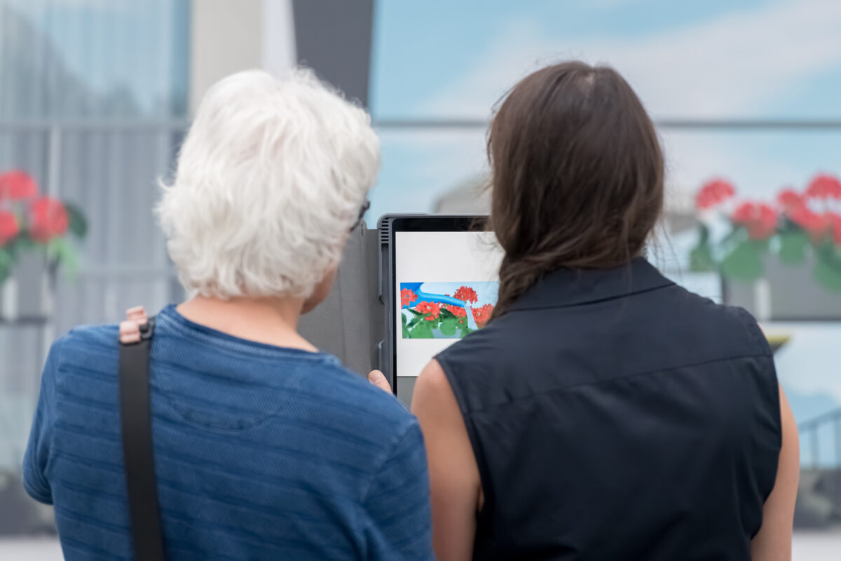 Personen schauen sich mit Tablets animierte Kunst an.