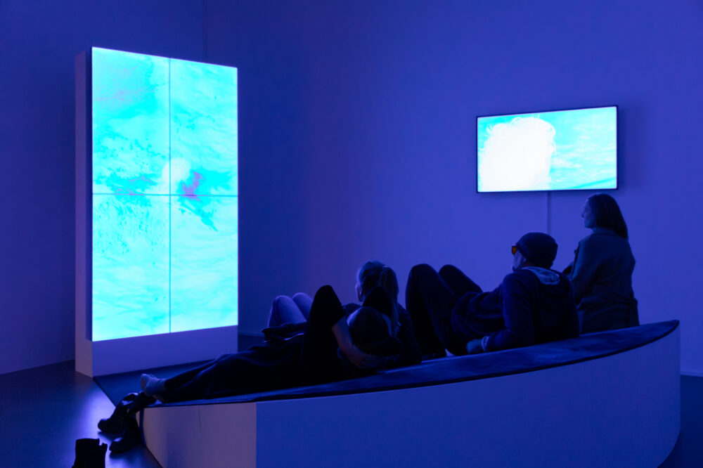Mehre liegende Personen schauen eine Videoinstallation im Kunsthaus an.