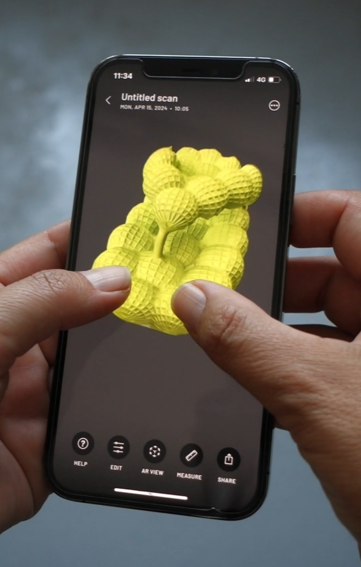 Zwei Finger vergrössern auf einem Smartphone ein dreidimensionales, gelbes Objekt