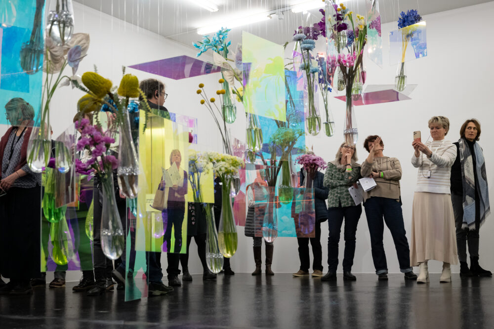 Foto von Personen, die vor einer Blumen für die Kunst Installation stehen