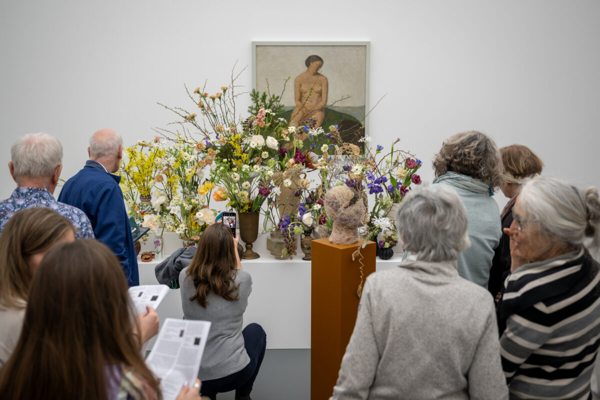 Foto von Personen, die vor einer Blumen für die Kunst Installation stehen