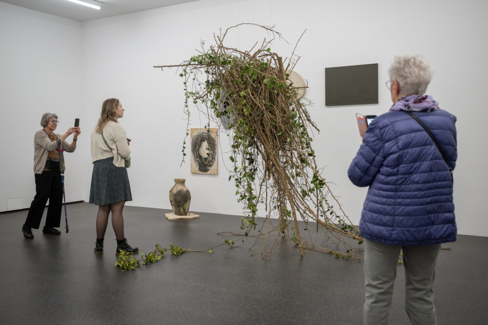 Foto von Personen, die vor einer Blumen für die Kunst Installation stehen
