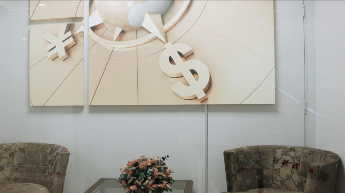 Ein Foto eines Büroraumes mit einem Bild an der Wand, auf dem ein Dollar- und ein Yen-Zeichen zu sehen ist.