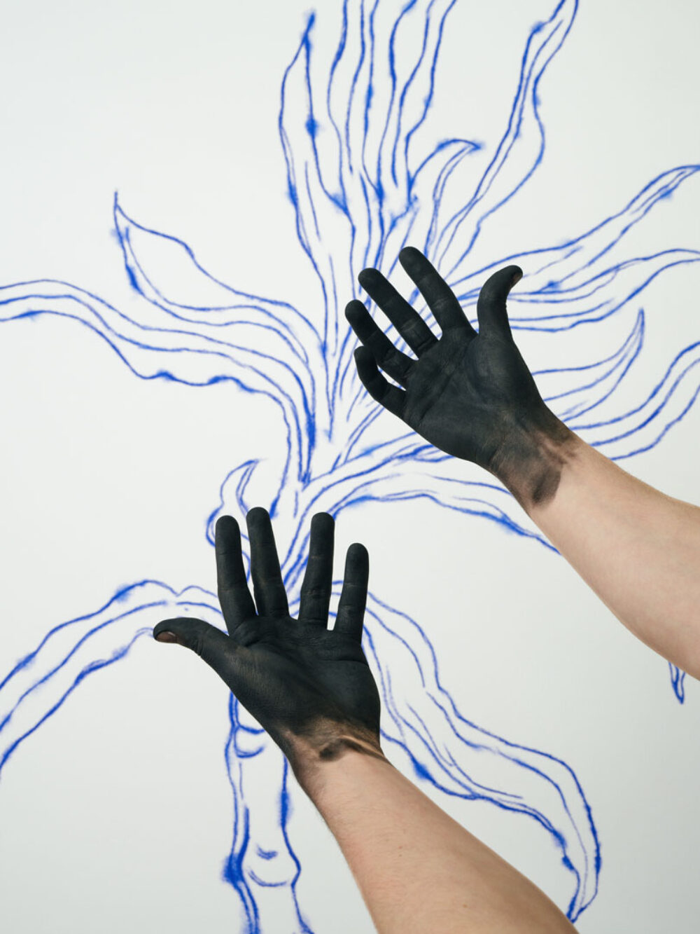 Von Farbe geschwärzte Hände vor einer blauen Pflanzenzeichnung