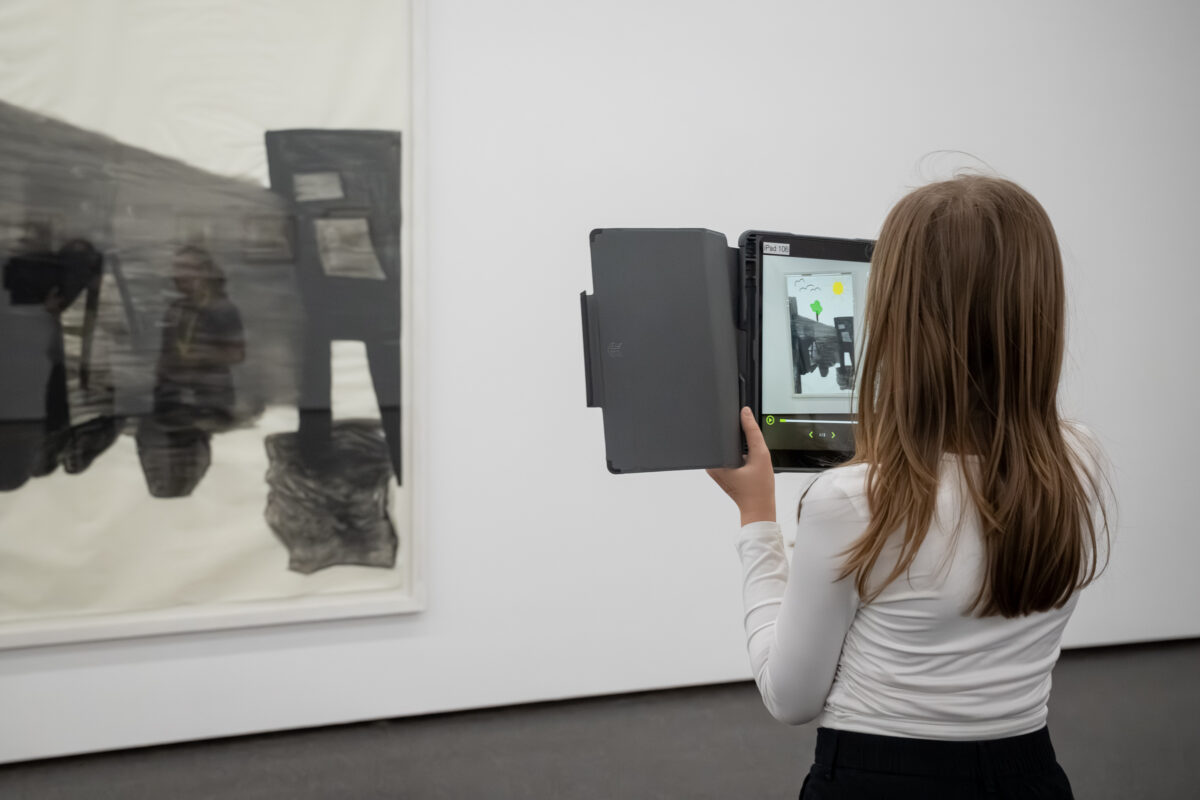 Kinder schauen mit einem Tablet in der Hand auf ein Sammlungswerk und erleben dank Augmented Reality eine animierte Version des Kunstwerkes