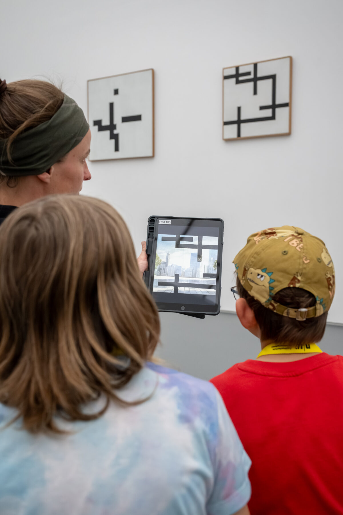 Kinder schauen mit einem Tablet in der Hand auf ein Sammlungswerk und erleben dank Augmented Reality eine animierte Version des Kunstwerkes