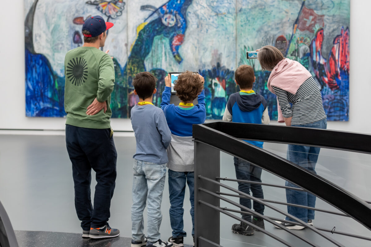 Kinder schauen mit einem Tablet in der Hand auf ein Sammlungswerk und erleben dank Augmented Reality eine animierte Version des Kunstwerkes