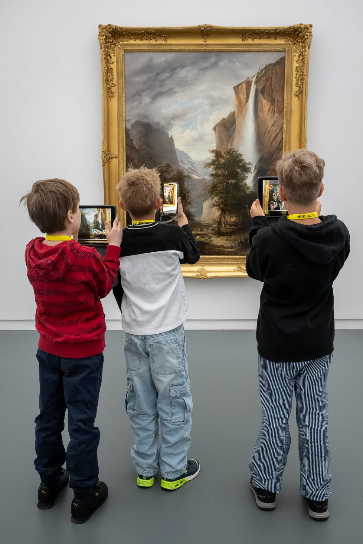 Kinder schauen mit einem Tablet in der Hand auf ein Sammlungswerk und erleben dank Augmented Reality eine animierte Version des Kunstwerkes
