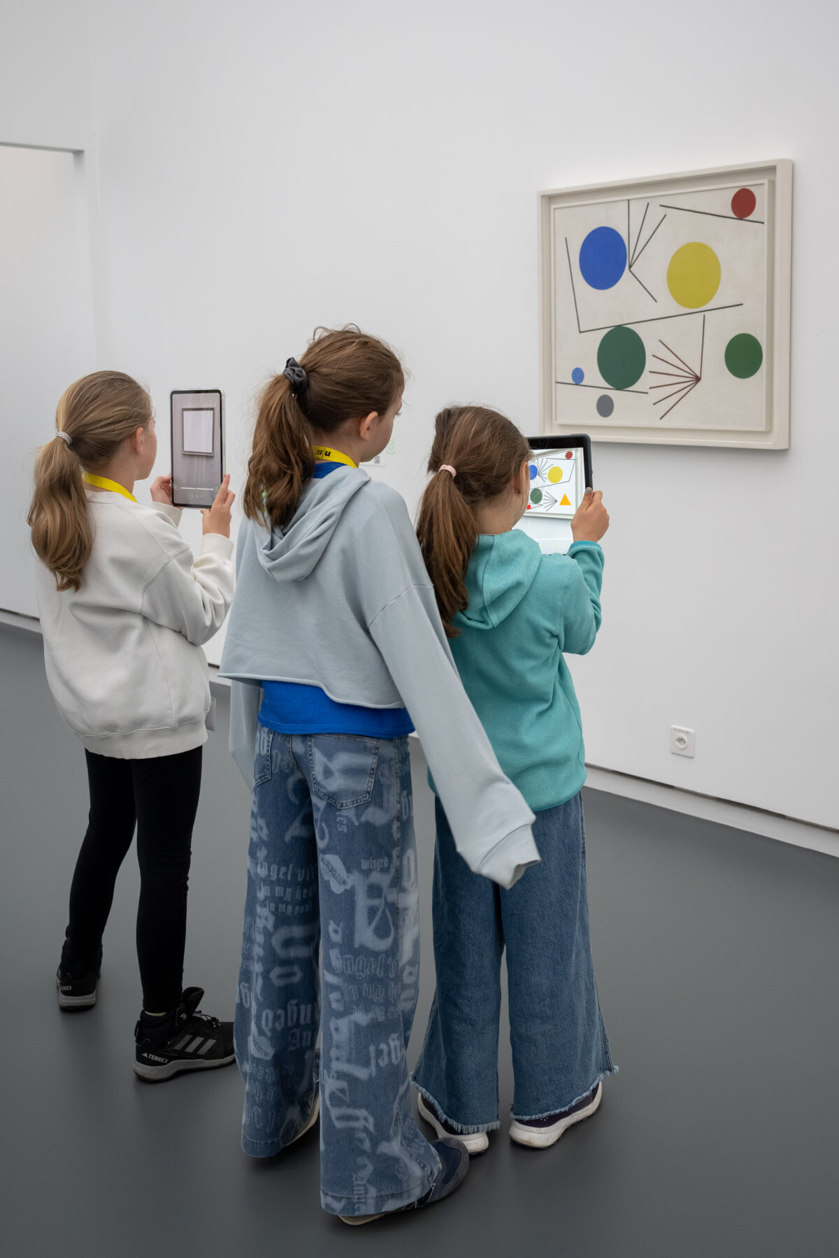 Kinder schauen mit einem Tablet in der Hand auf ein Sammlungswerk und erleben dank Augmented Reality eine animierte Version des Kunstwerkes