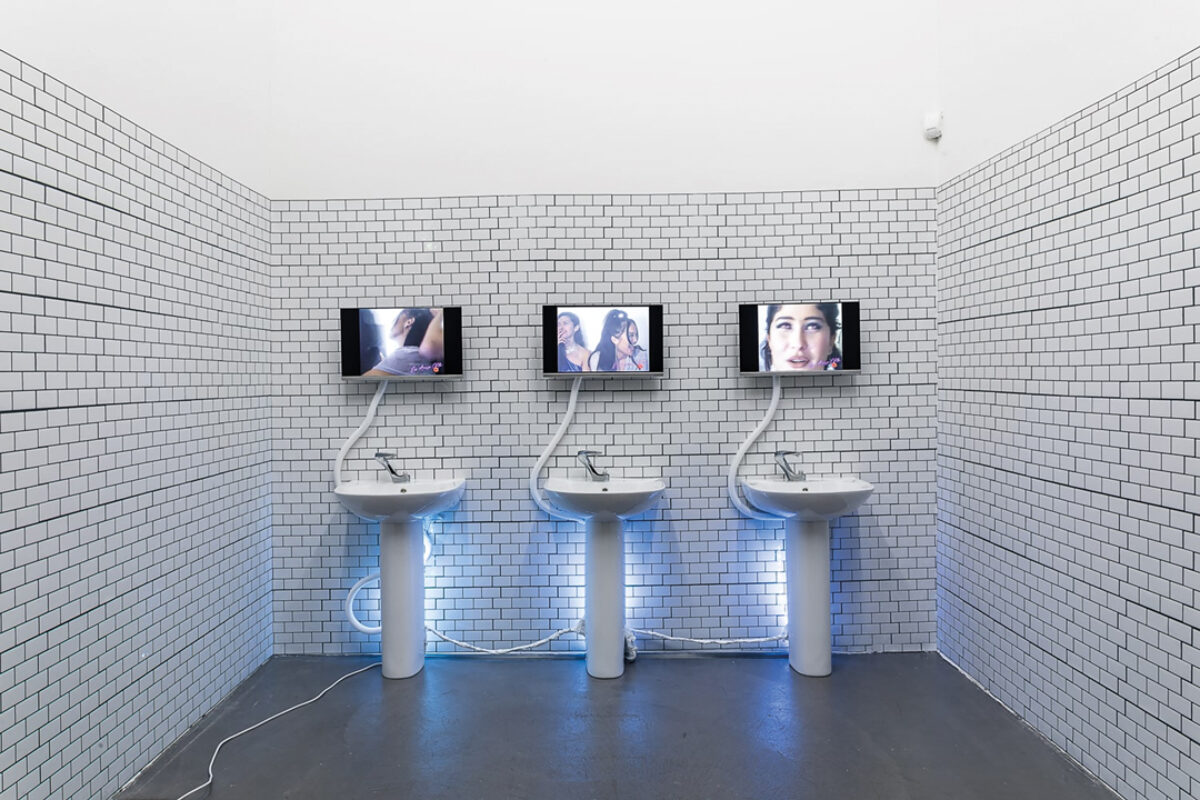 Foto einer Installation von Shamiran Istifan, das wie ein öffentliche Toilette mit Bildschirmen aussieht