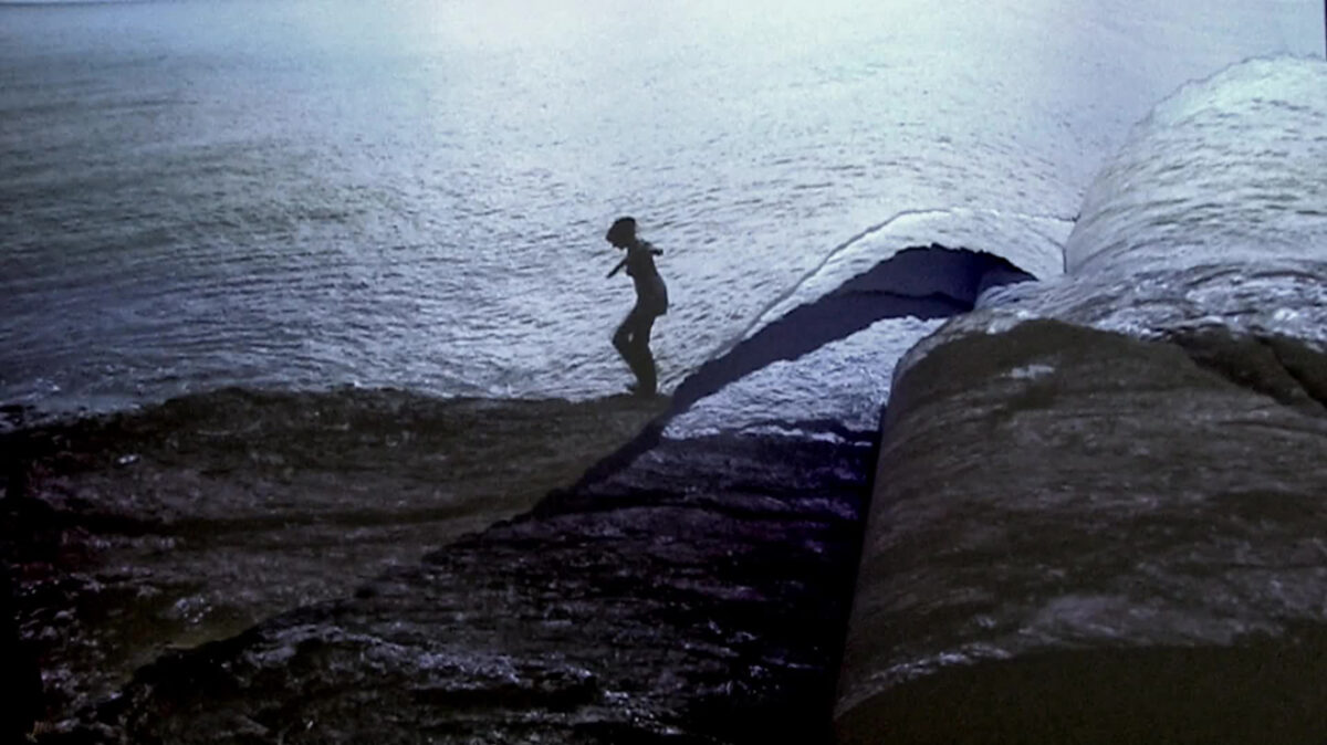 Videostill von Judith Albert, dass ein Mädchen am Strand entlang laufend zeigt.