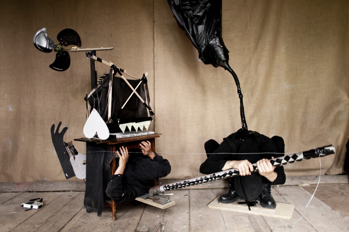 Videostill von Augustin Rebetez, dass zwei Personen zeigt, die selber gebastelte Instrumente halten.