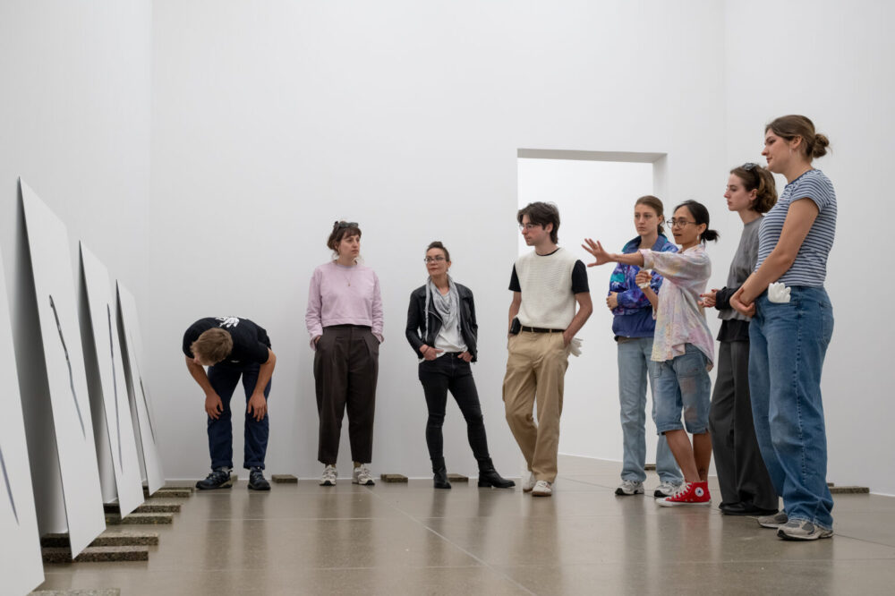 Eine Gruppe von jungen Menschen diskutiert gemeinsam über die Hängung der Bilder.