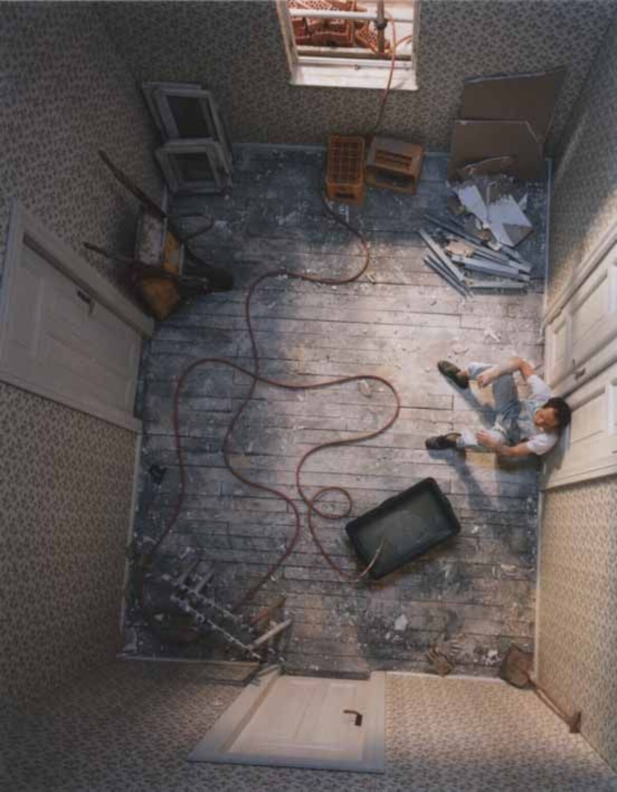 Foto eines Innenraums mit einem sitzenden Handwerker von oben aufgenommen.