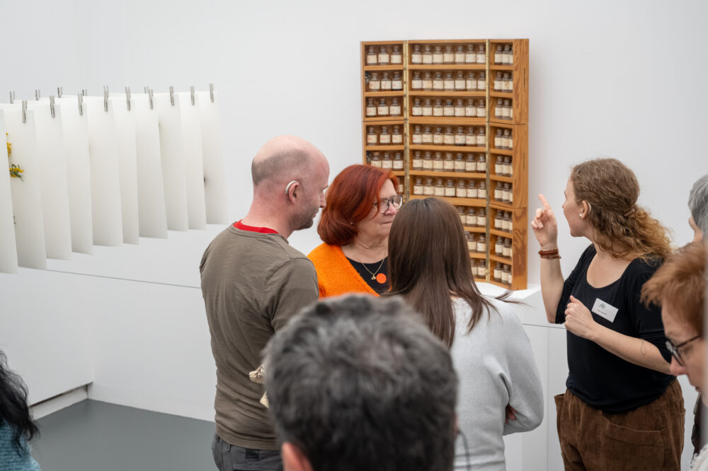 Eine Vermittlungsperson vermittelt mithilfe von Duftröhrchen ein Blumen für die Kunst Werk.