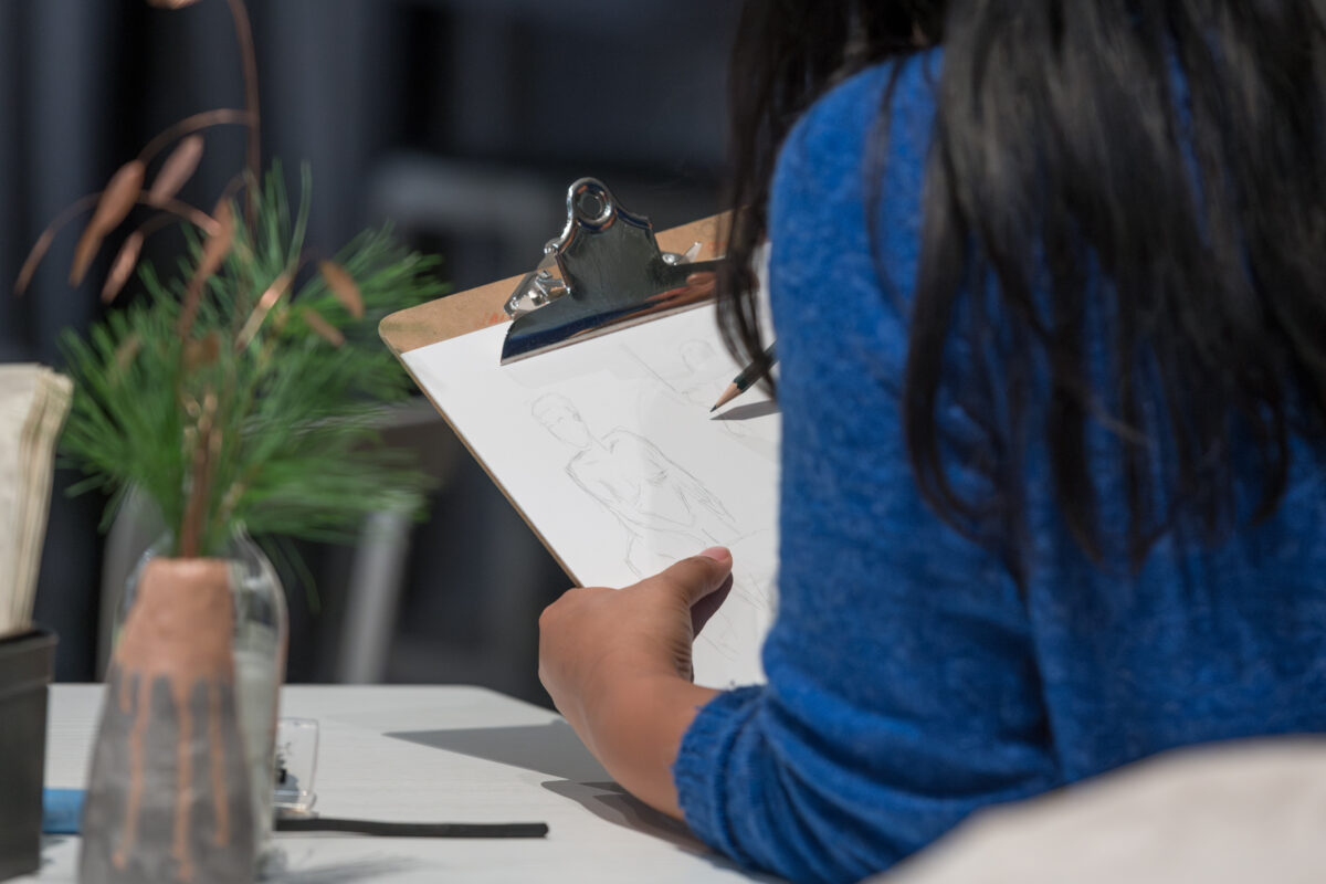 Foto einer Person, die in ein Skizzenbuch skizziert.