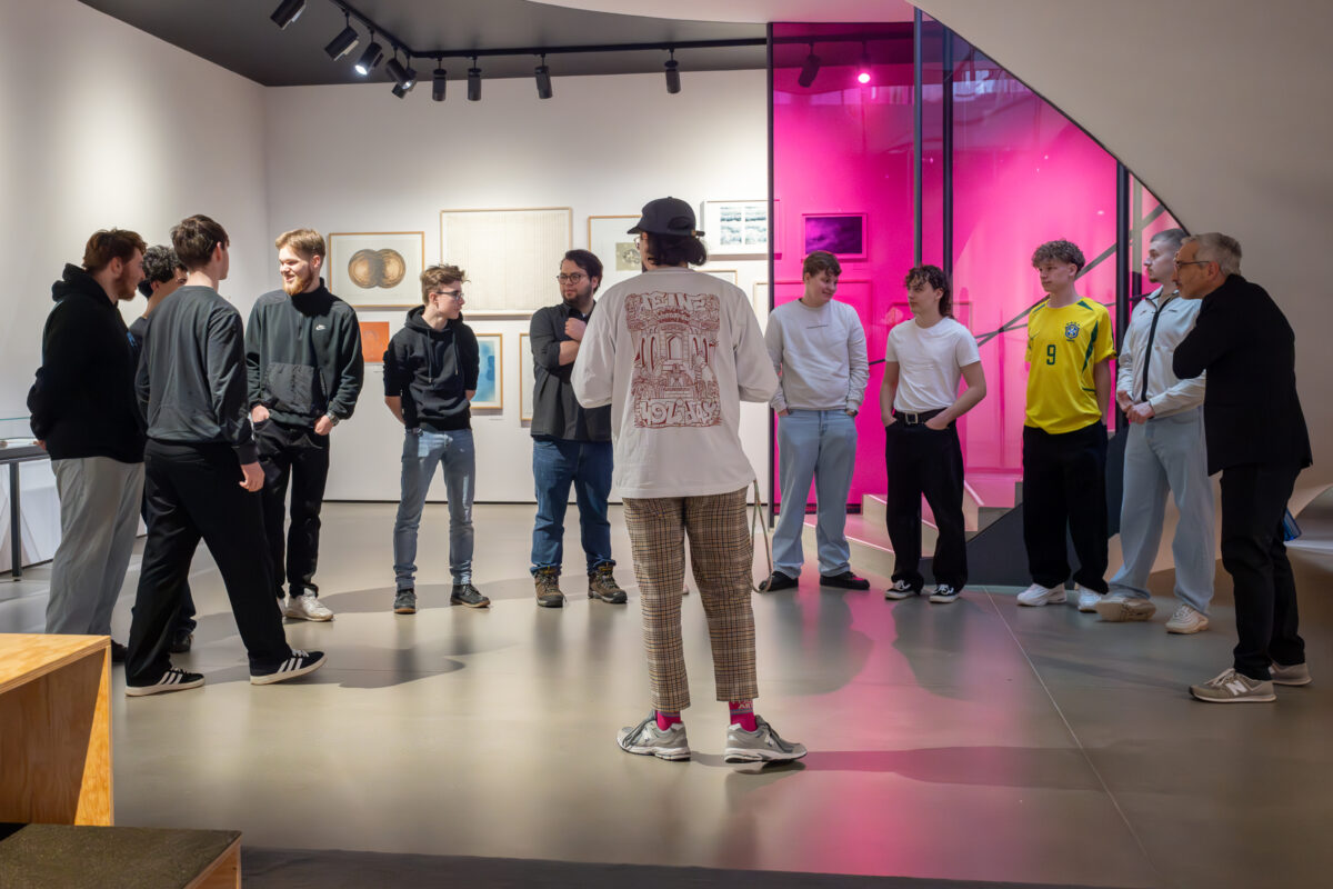 Eine Schulklasse hört einem Vermittler zu im Freiraum des Kunsthauses.