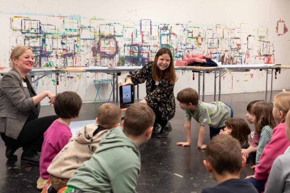 Kinder hören einer Vermittlerin im Atelier zu.