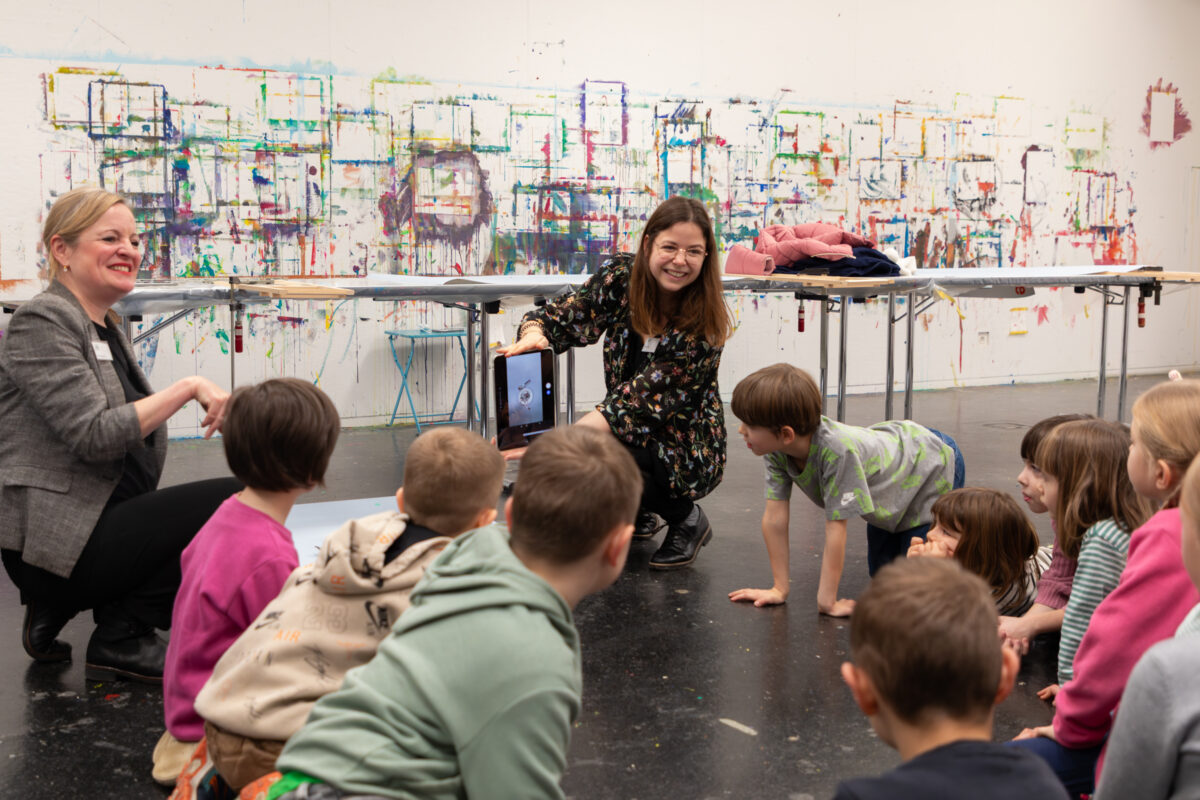 Kinder hören einer Vermittlerin im Atelier zu.