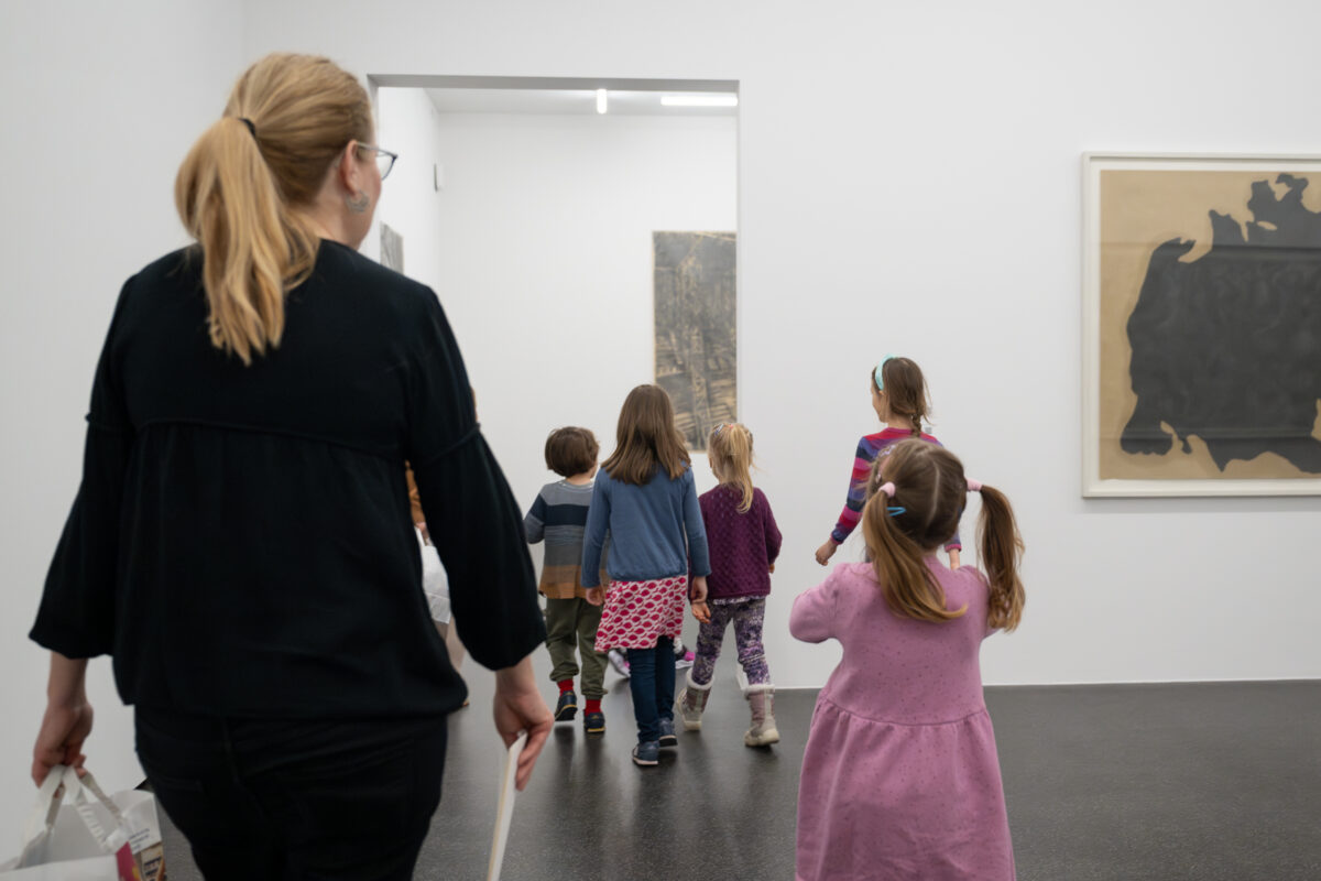 Eine Gruppe von Kindern und eine Vermittlerin laufen gemeinsam durch das Museum.